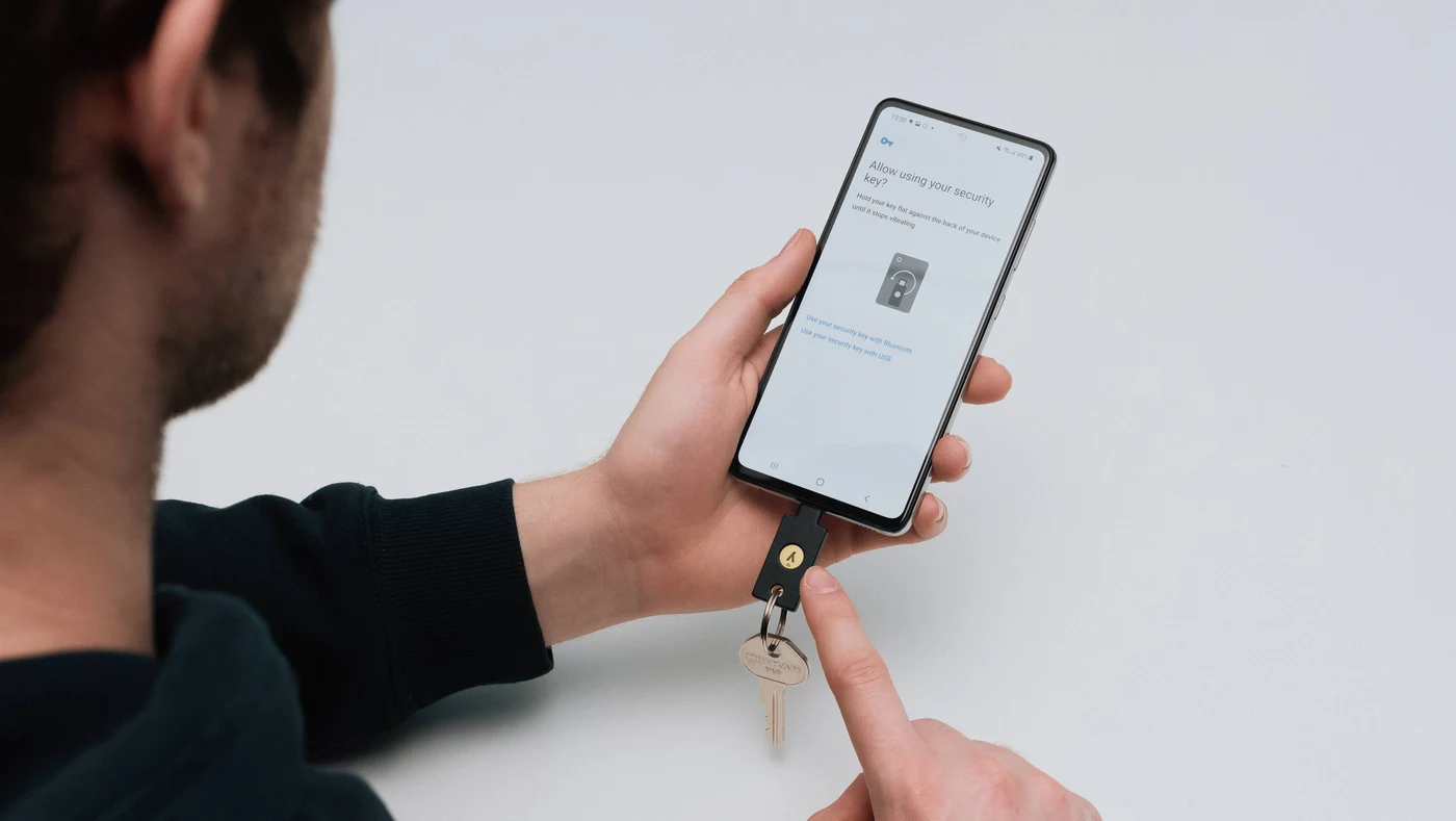 Muškarac drži Android mobitel s YubiKeyjem 5C NFC u USB-C priključku, a zaslon traži sigurnosni ključ